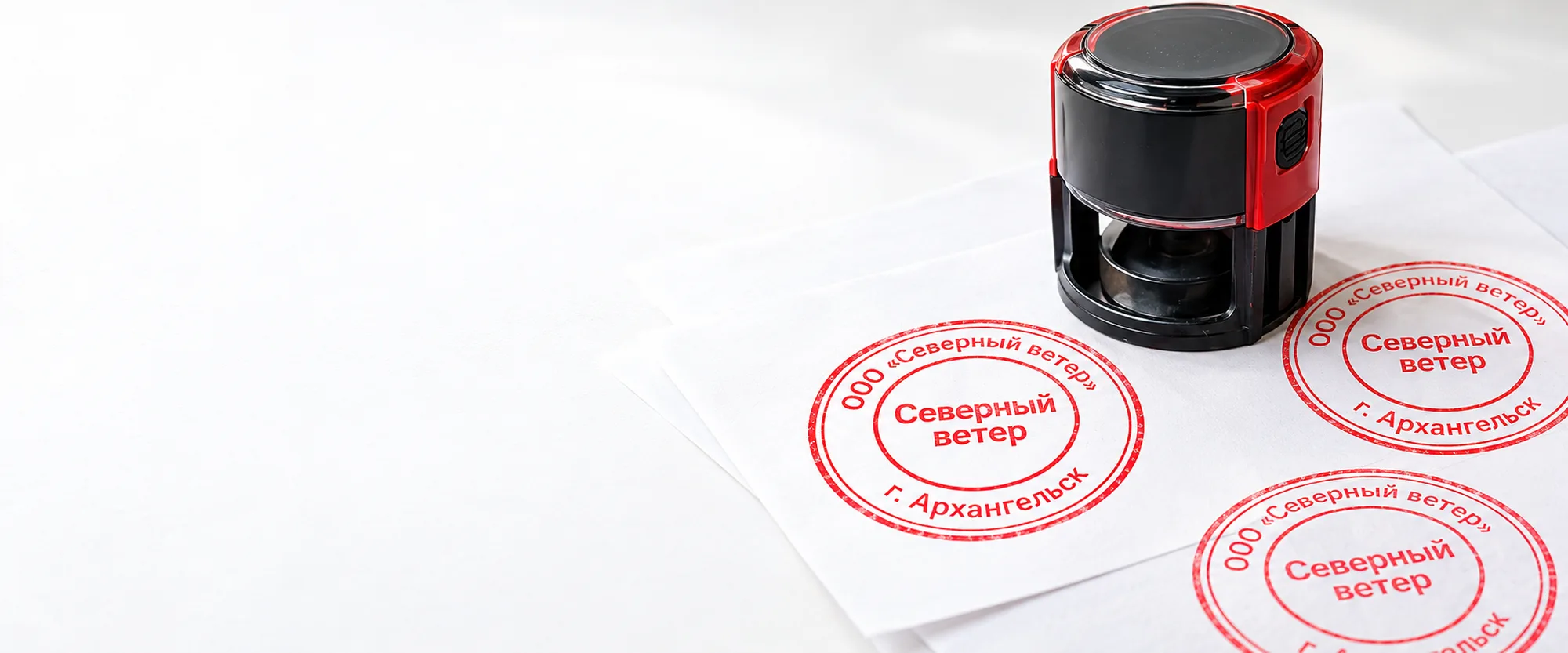 Автоматическая оснастка на листах бумаги, рядом свежие красные оттиски круглой печати